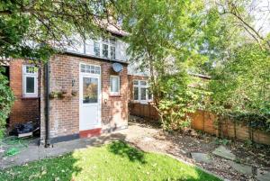 a brick house with a white door and a fence at Beautiful 1-Bed Apartment with Garden in London in London