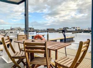 een houten tafel en stoelen op het dek van een boot bij Houseboat orange Sneekermeer in Offingawier