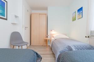 een slaapkamer met 2 bedden, een stoel en een tafel bij Wohnpark Heisterbusch Ferienhaus 13d in Kellenhusen