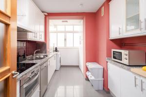 uma cozinha com paredes vermelhas e armários brancos em Nordik Apartments Urban - Playa Virginia "Hanko" em Málaga