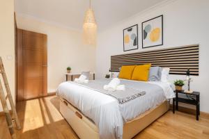 1 dormitorio con 1 cama blanca grande con almohadas amarillas en Nordik Apartments Urban - Playa Virginia "Hanko" en Málaga