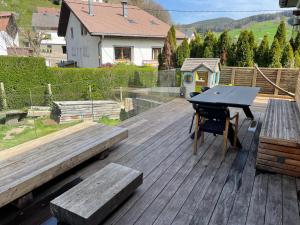 a wooden deck with a ping pong table and a bench at Joli logement 6 à 8 pers avec terrasse La Cigale in Orbey