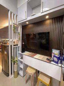 cocina con encimera con 2 taburetes y TV en Grass Residences Charming Staycation, en Manila
