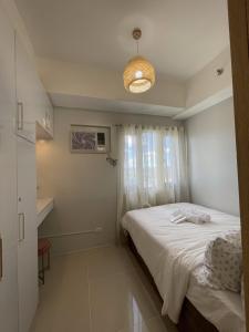1 dormitorio con cama blanca y ventana en Grass Residences Charming Staycation, en Manila