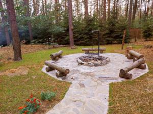 eine Feuerstelle in einem Park mit Holzscheiten drum herum in der Unterkunft Domek pod sosnami in Grodziczno