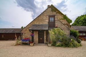 a brick house with a balcony and flowers in front of it at Old Dairy Cottage - Cosy and Luxurious! in Buckinghamshire