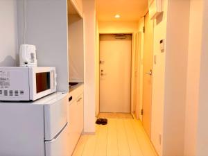 eine Küche mit einer Mikrowelle auf dem Kühlschrank in der Unterkunft IXO Ts1 in Tokio