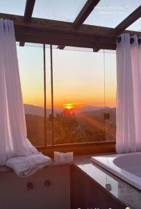 uma casa de banho com banheira e vista para o pôr-do-sol em Chale Vista Encantada em Lavras Novas