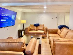 a living room with brown leather furniture and a screen at Breathtaking Views Near Lake Placid and Whiteface in Wilmington