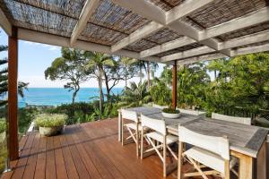 una terrazza all'aperto con tavolo, sedie e vista sull'oceano di The Birds Nest - Hidden Oasis a Bilgola