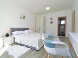 a white bedroom with a bed and two chairs at Holiday Home Skelin by Interhome in Drinovci