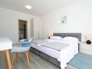 a white bedroom with a bed and a desk and a chair at Holiday Home Skelin by Interhome in Drinovci