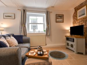 un salon avec un canapé et une télévision dans l'établissement Honeymoon Cottage, à Bideford