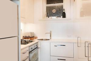 a white kitchen with a sink and a stove at Dungawon - Beachfront in Sydney