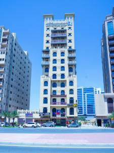 a tall white building with cars parked in front of it at Palette Royal Reflections Hotel and Spa Dubai in Dubai