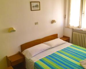 een slaapkamer met een bed met een kleurrijk gestreepte deken bij Hotel Alessi** Rimini in Rimini