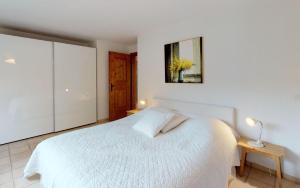 a white bedroom with a white bed and a mirror at Nina - b42985 in Celerina