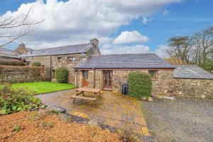 a stone house with a bench in front of it at Damson Cottage in Waberthwaite