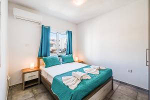 een slaapkamer met een bed met blauwe gordijnen en een raam bij Ayia Napa Central Apartment by Ezoria Villas in Ayia Napa