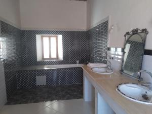 a bathroom with two sinks and a tub and a mirror at Hotel et Restaurant Riad Amodou in Tinerhir
