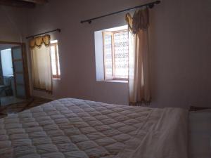 a bedroom with a large bed and two windows at Hotel et Restaurant Riad Amodou in Tinerhir