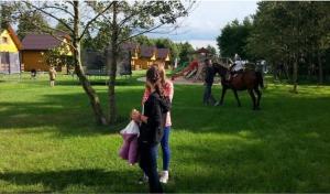 a couple of people walking in the grass with a horse at Ferienwohnung in Glenwko mit Terrasse, Garten und Grill in Gleźnowo