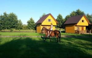 a woman riding a horse in front of a house at Ferienwohnung in Glenwko mit Terrasse, Garten und Grill in Gleźnowo