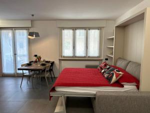 a bedroom with a red bed and a dining room at Modern apartment on the beach in Nago-Torbole