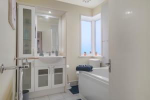 a bathroom with a tub and a sink and a toilet at Newly Renovated Flat in London w/FREE Parking in Hendon