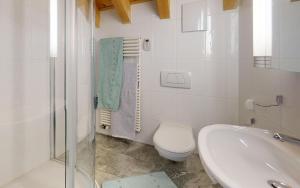 La salle de bains blanche est pourvue de toilettes et d'un lavabo. dans l'établissement Sur Crasta, à Celerina
