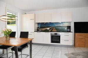 uma cozinha com armários brancos e uma mesa de madeira em Ferienwohnung Bruttel em Gaienhofen