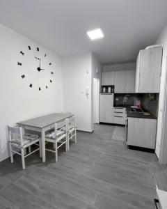 a kitchen with a table and a clock on the wall at Appartamento La Corte in Levico Terme