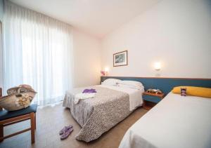 a hotel room with two beds and a window at Hotel Taormina in Riccione