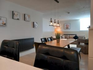 a dining room with a table and leather chairs at Apartment 1 Old Conservative Club in Historic Town Pass the Keys in Caernarfon