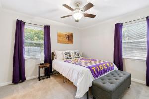 um quarto com cortinas roxas, uma cama e uma ventoinha de tecto em LSU Slammer Arcade 4 5 mile to LSU Private Yard em Baton Rouge