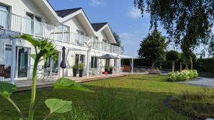 una gran casa blanca con un gran patio en BADEBUDE 3 Ferienhaus im Hampton Style, en Oldenburg in Holstein