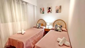 duas camas num quarto com lençóis cor-de-rosa em VORA GANDIA BEACH - Alquiler Familias em Los Mártires