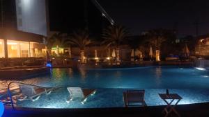 a swimming pool at night with chairs and palm trees at Rosa Bela Hotel & Convention Center in Puerto Ordaz +34 photos