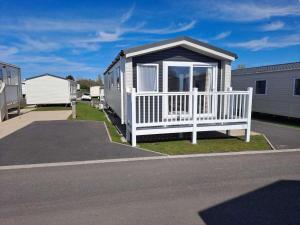 ein winziges Haus mit einer Veranda und einem weißen Zaun in der Unterkunft Edwards Holiday Home in Blackpool