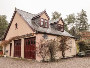uma casa com uma grande garagem com portas vermelhas em Purlie Lodge Apartment em Inverness