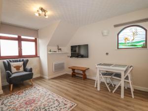 a living room with a table and a chair at Purlie Lodge Apartment in Inverness