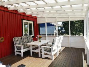 eine Terrasse mit einem weißen Tisch und 2 Stühlen in der Unterkunft Buntes Schwedenhaus Lillebror in Fågelfors