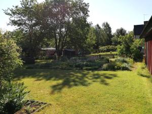 einen Garten mit einem Schatten eines Baumes auf dem Gras in der Unterkunft Buntes Schwedenhaus Lillebror in Fågelfors