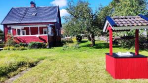 ein rotes Haus mit einer roten Box davor in der Unterkunft Buntes Schwedenhaus Lillebror in Fågelfors