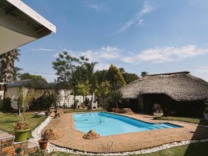 a swimming pool in a yard with a thatched building at Contemporary Gem: Studio with Serene Pool View in Newcastle