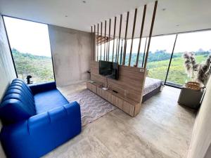 sala de estar con sofá azul y TV en Glamping Cabaña de Lujo, en Girón