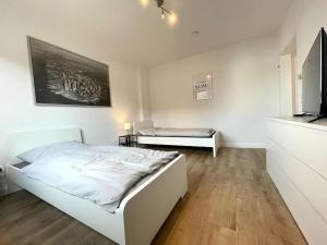 ケーニヒスヴィンターにあるCharmantes Apartment mit 3 Bettenのベッドとソファのある白い寝室 +2枚の写真