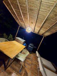 eine Terrasse mit einem Holztisch und Stühlen unter dem Dach in der Unterkunft Glamping Cabaña de Lujo in Girón