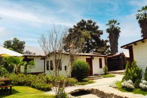 a house with a garden and palm trees at Los Andes - Restaurant & Bungalows in Cieneguilla