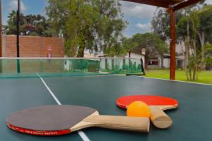 two tennis rackets and balls on a ping pong table at Los Andes - Restaurant & Bungalows in Cieneguilla